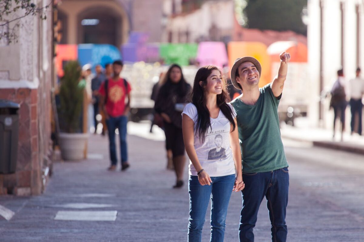 Smiling couple holding hands and exploring a lively city street.