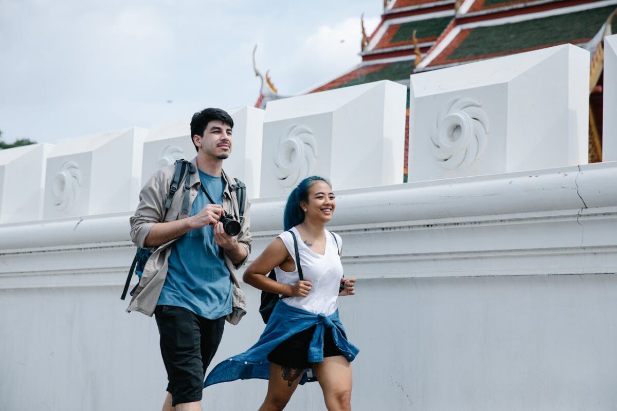 A cheerful couple exploring an outdoor landmark with traditional architecture.